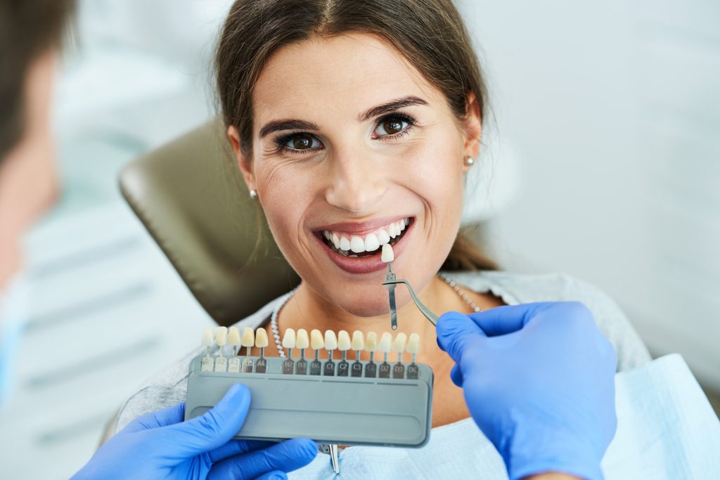 Male dentist and woman choosing tooth shade in dentist office